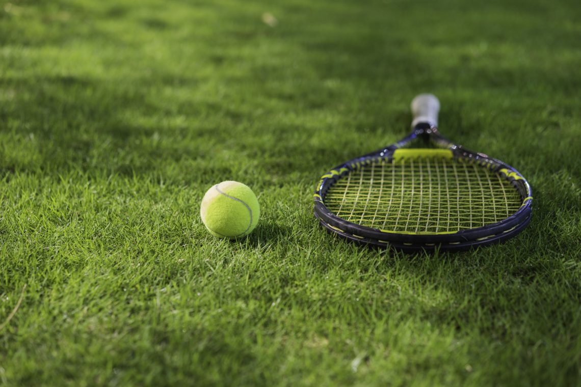 Tennis ball with racket on wet grass after raining